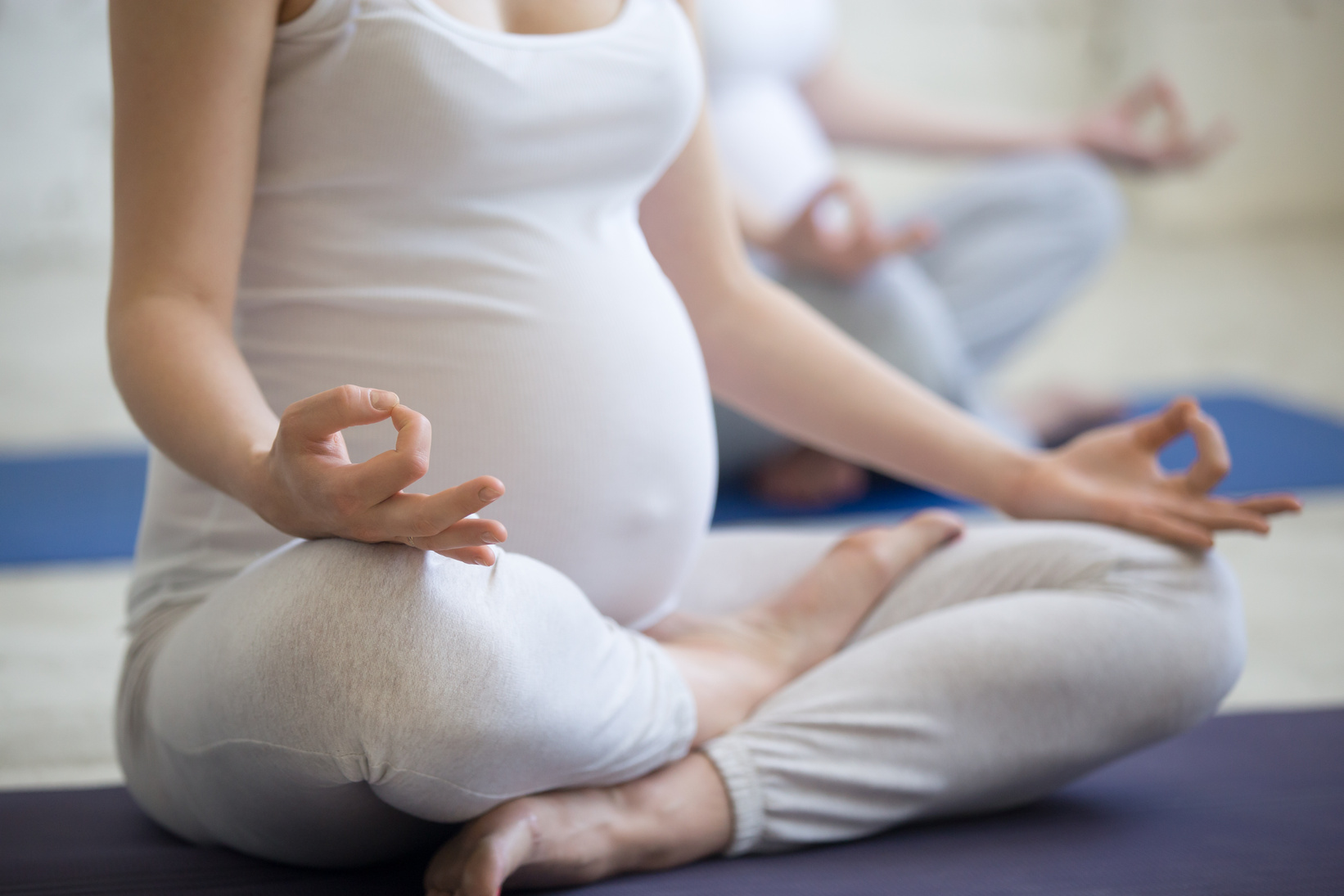 Pregnant young women doing prenatal yoga. Close-up of torso